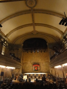 Inside Wilton's Music Hall. Large arching roof. Stage at far end.